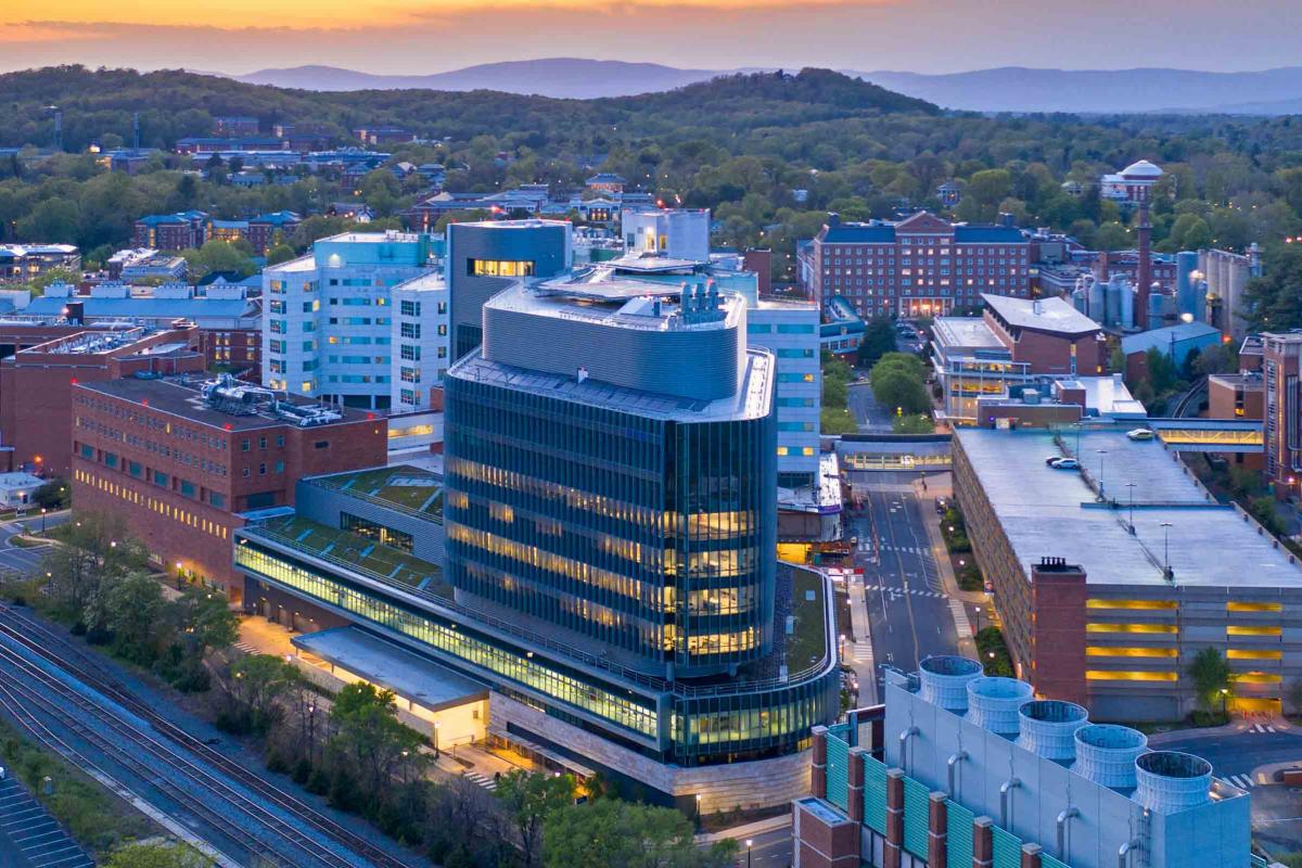 A photo of UVA hospital as the sun is rising over the mountains behind it.